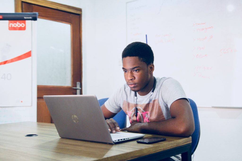 Jeune homme regardant fixement un écran d'ordinateur installé sur un bureau dans une salle de classe